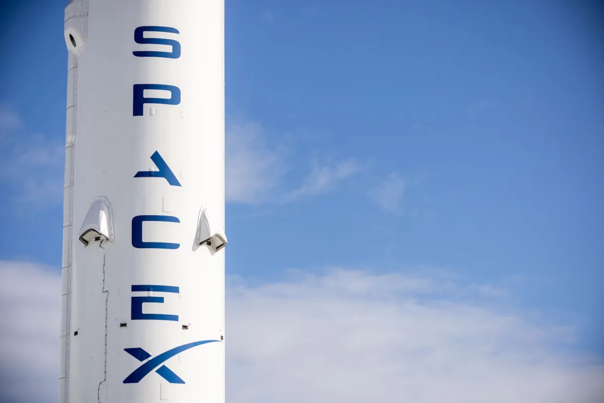 A stylized graphic representing SpaceX's integration of its AI division, XAI, with elements suggesting satellite communication and data processing.